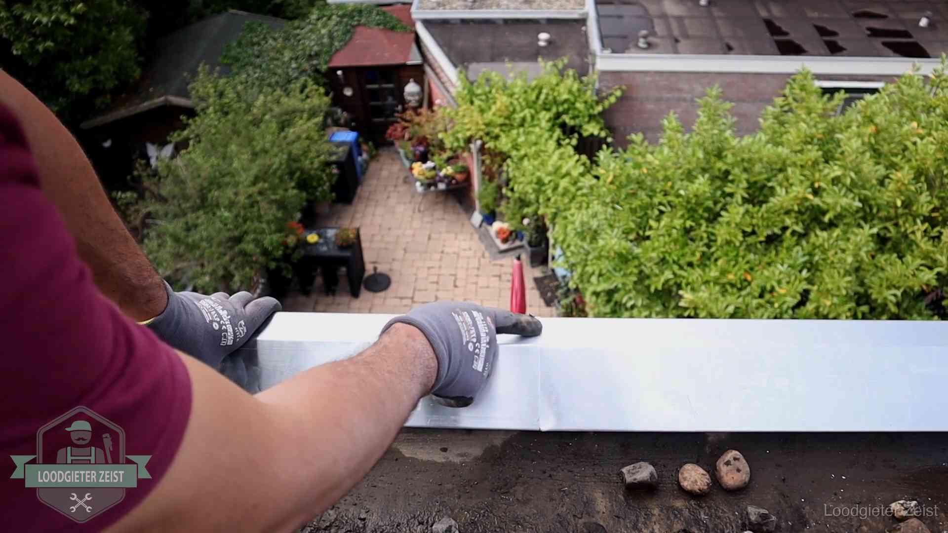 Vakman plaatst een daktrim op de dakrand van een woning in Zeist