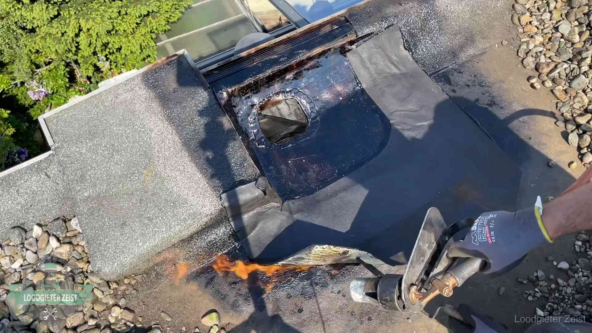 Dakdekker brandt bitumen rond een doorvoer tijdens een daklekkage-reparatie in Zeist