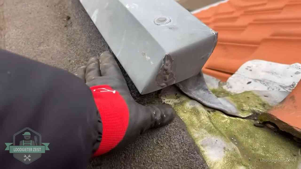 Controle van een zinken hemelwaterafvoer met loodslab bij dakpannen in Zeist