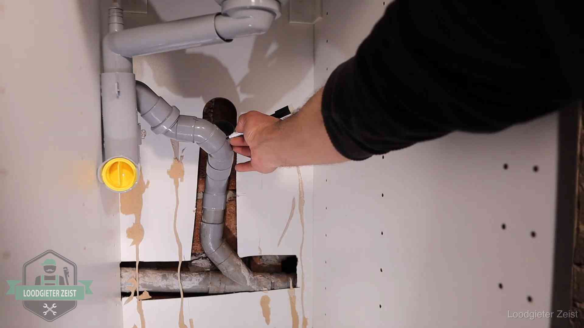 Loodgieter voor verhuurders en bedrijven in Zeist Loodgieter markeert een pvc-afvoerbuis onder een gootsteen in Zeist