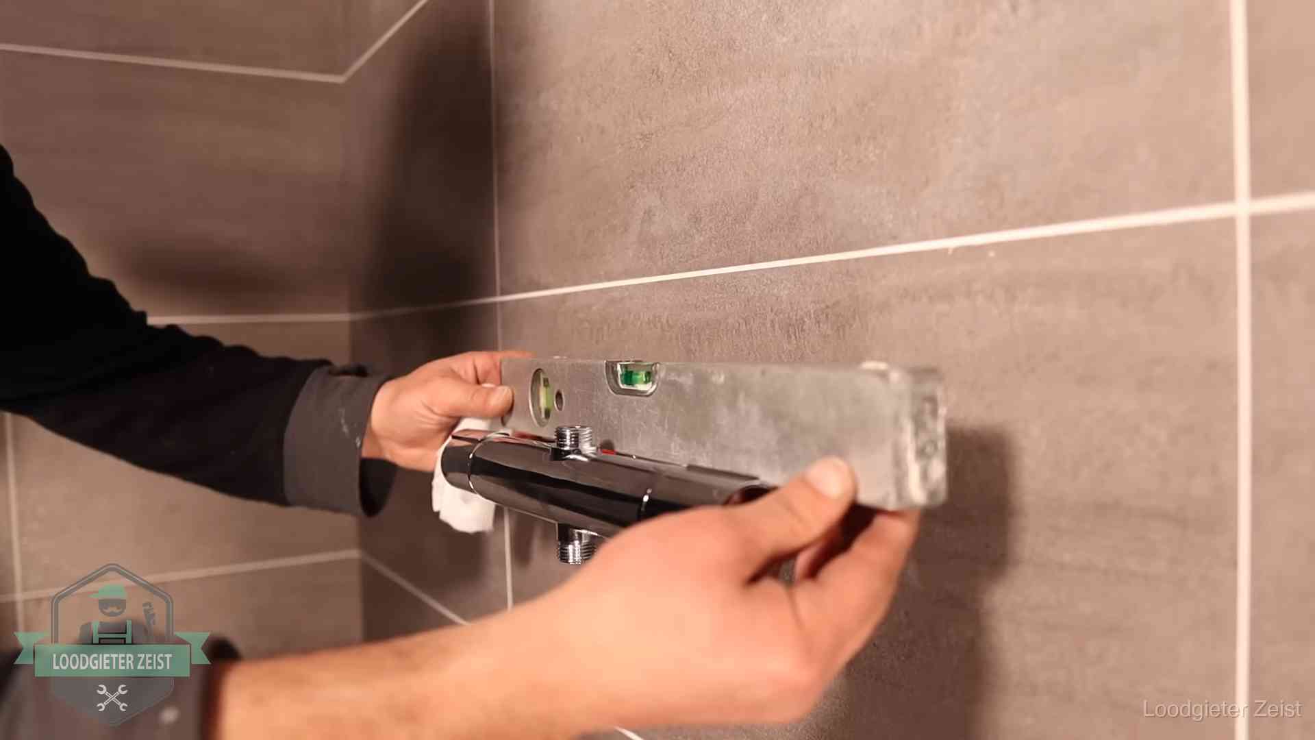 Loodgietersbedrijf voor sanitair in Zeist Loodgieter lijnt een douchekraan uit met een waterpas in een woning in Zeist