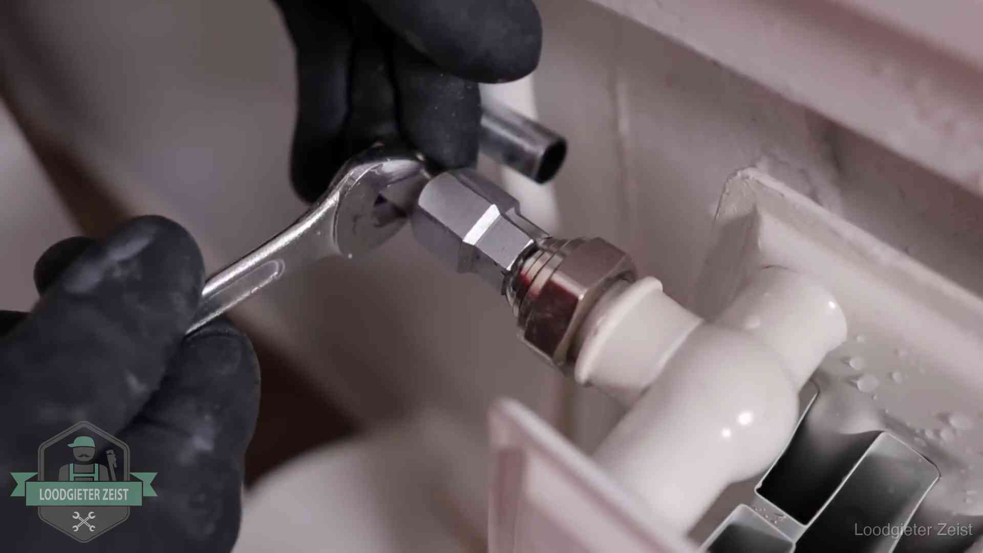 Steeksleutel draait een wartelkoppeling op een radiatorkraan aan in Zeist