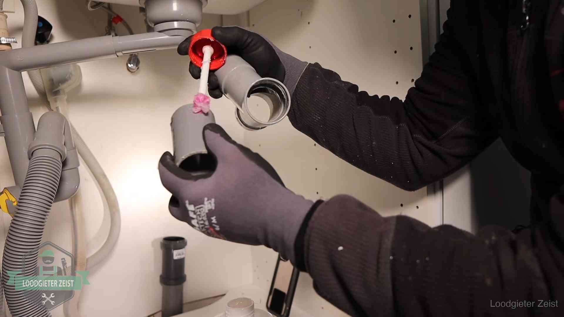 Loodgieter demonteert en reinigt de sifon onder een keukenkast in Zeist