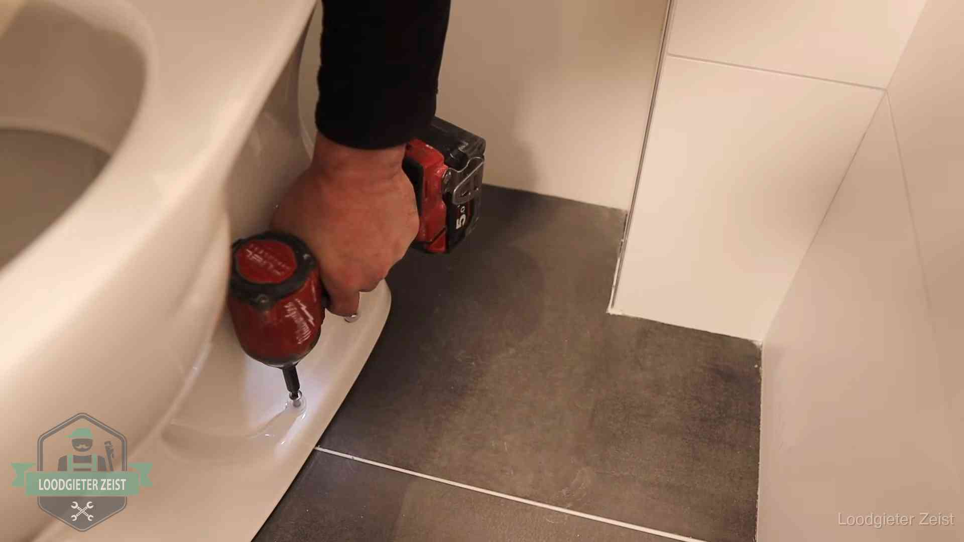 Kosten wc ontstoppen in Zeist Loodgieter zet de voet van een wc-pot vast op de tegelvloer in Zeist